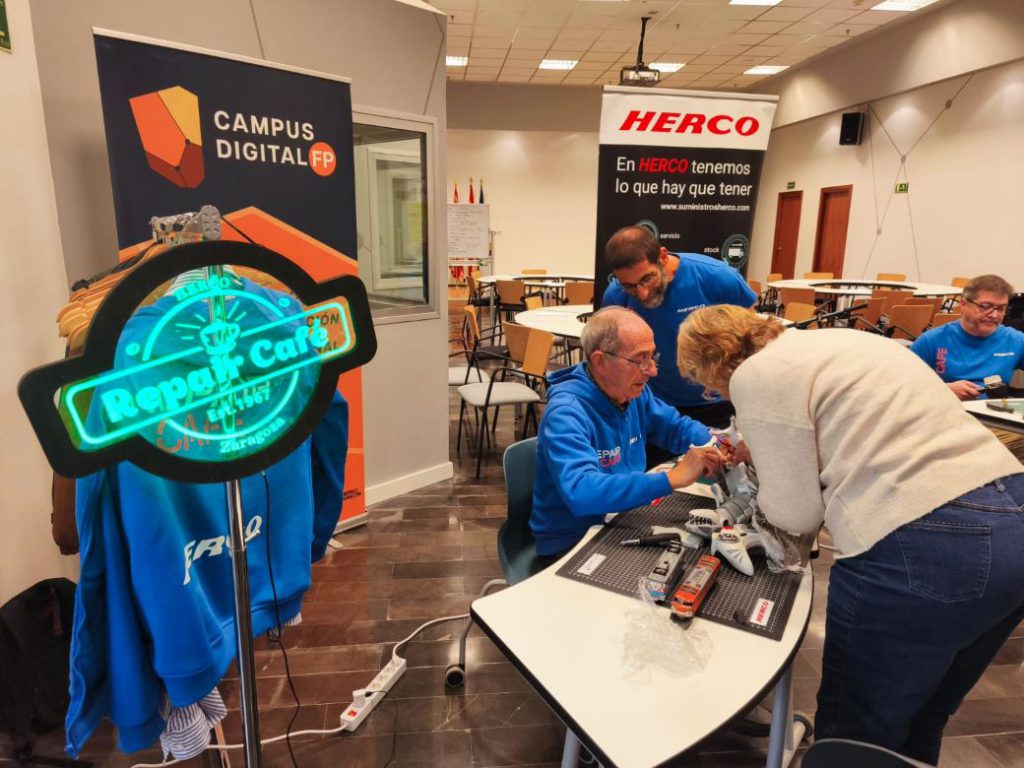 Voluntarios de Herco entregando un portátil reparado en evento de economía circular.